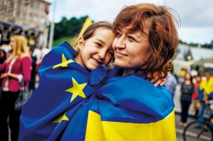 Kobieta z dzieckiem owinięte we flagi Ukrainy i Unii Europejskiej podczas demonstracji w Kijowie fot.Roman Pilipey/EPA